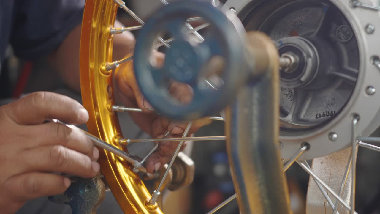 técnico hombre trabajando rueda de motocicleta tiene rayos tejer en herramienta mecánica nueva rueda de acero