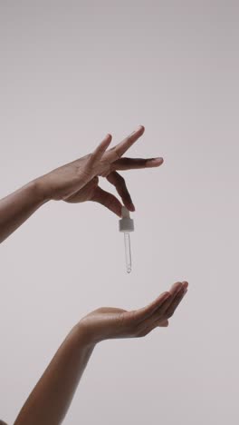 close up of woman squeezing dropper from bottle of beauty product on white background 3