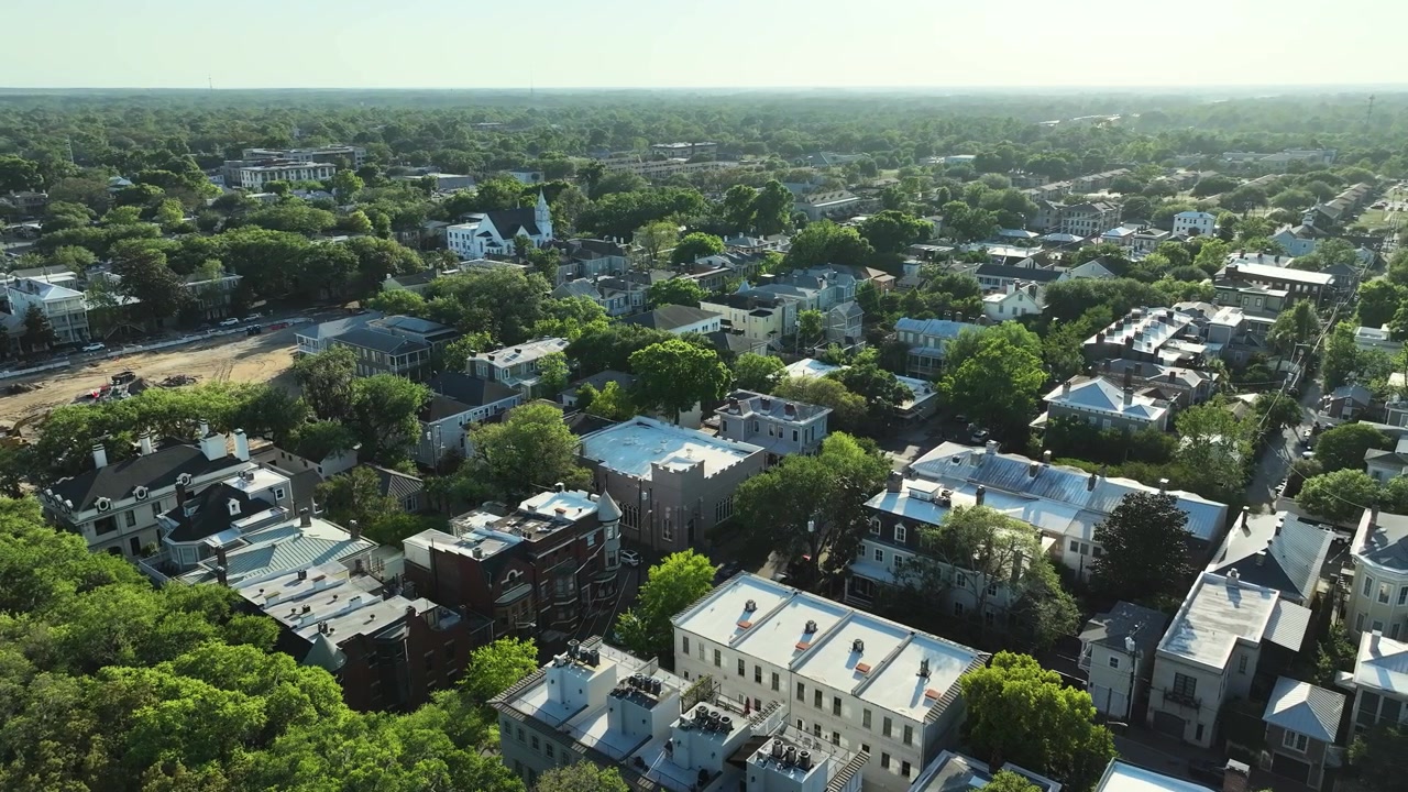 Aerial drone view of Savannah's South Historic District in Georgia, showcasing rows of colorful historic homes, tree-canopied streets, and timeless Southern charm.