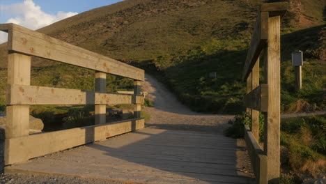 walkway over bridge heading towards countryside path at golden hour, low angle panning shot