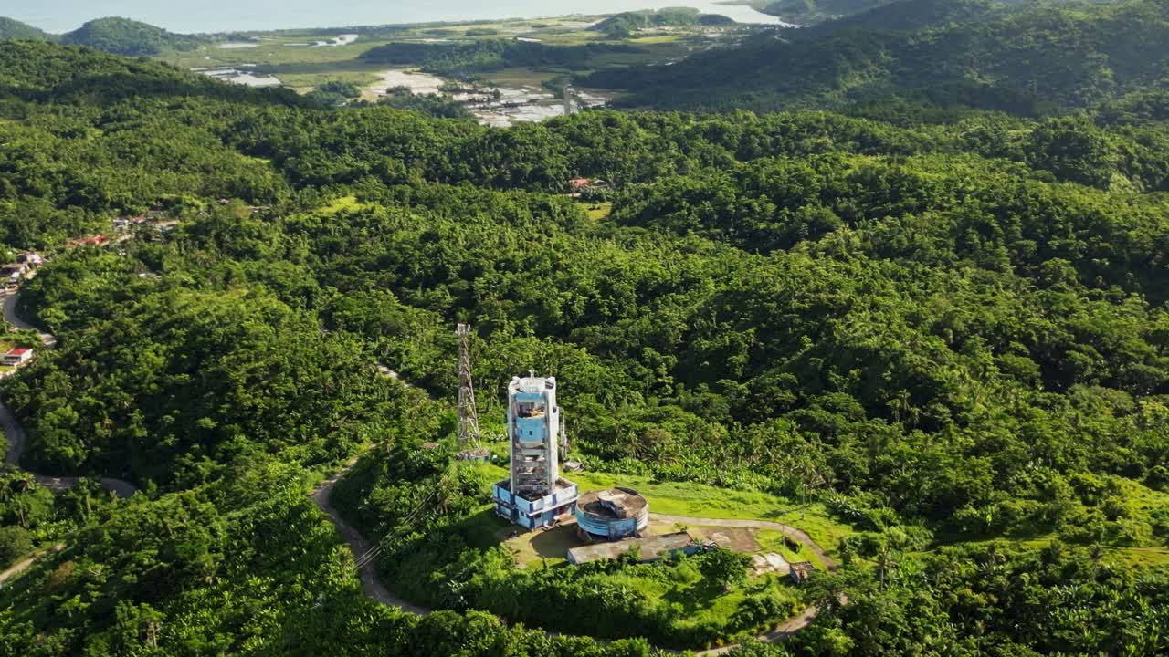 Aerial pullback of PAGASA weather radar station atop hills overlooking the lush tropical island Catanduanes, Philippines during daytime