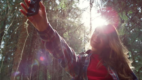 Traveler-taking-selfie-on-mobile-phone-in-forest.-Woman-showing-tongue-at-camera