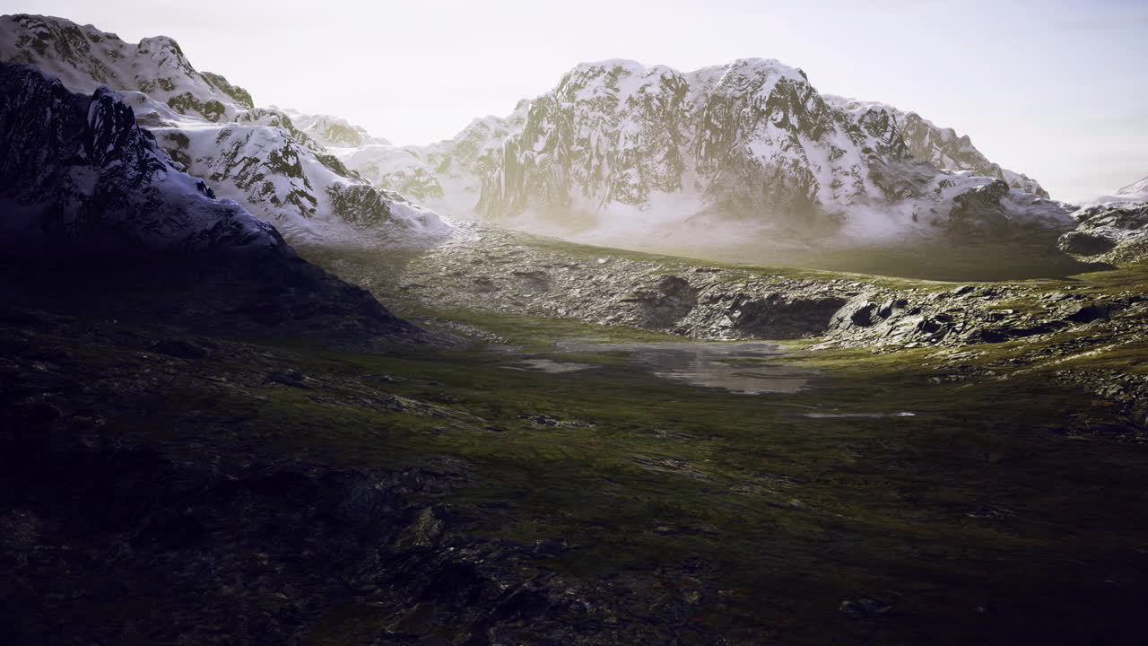 Mountain landscape with snow capped peaks and lush green valley at dusk