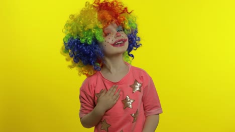 la niña payasa con la peluca colorida dice algo interesante. divirtiéndose, sonriendo. halloween