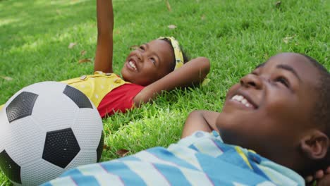animation of happy african american siblings lying on lawn and looking at sky