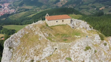 aerial drone view of the hermitage of aitzorrotz on top of a mountain in the basque country