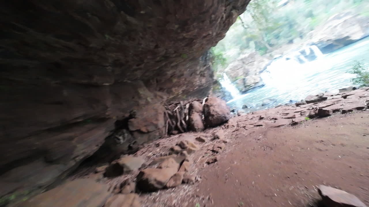 FPV drone shot capturing cascades gushing over rock ledges into a blue pool, in Gruta India Grotto, Misiones Argentina