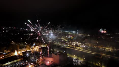 Fuegos-Artificiales-En-Una-Pequeña-Ciudad,-Explotando-En-Una-Variedad-De-Colores,-Incluidos-Rojo,-Verde,-Azul,-Amarillo-Y-Naranja,-Contra-Un-Cielo-Nocturno-Oscuro