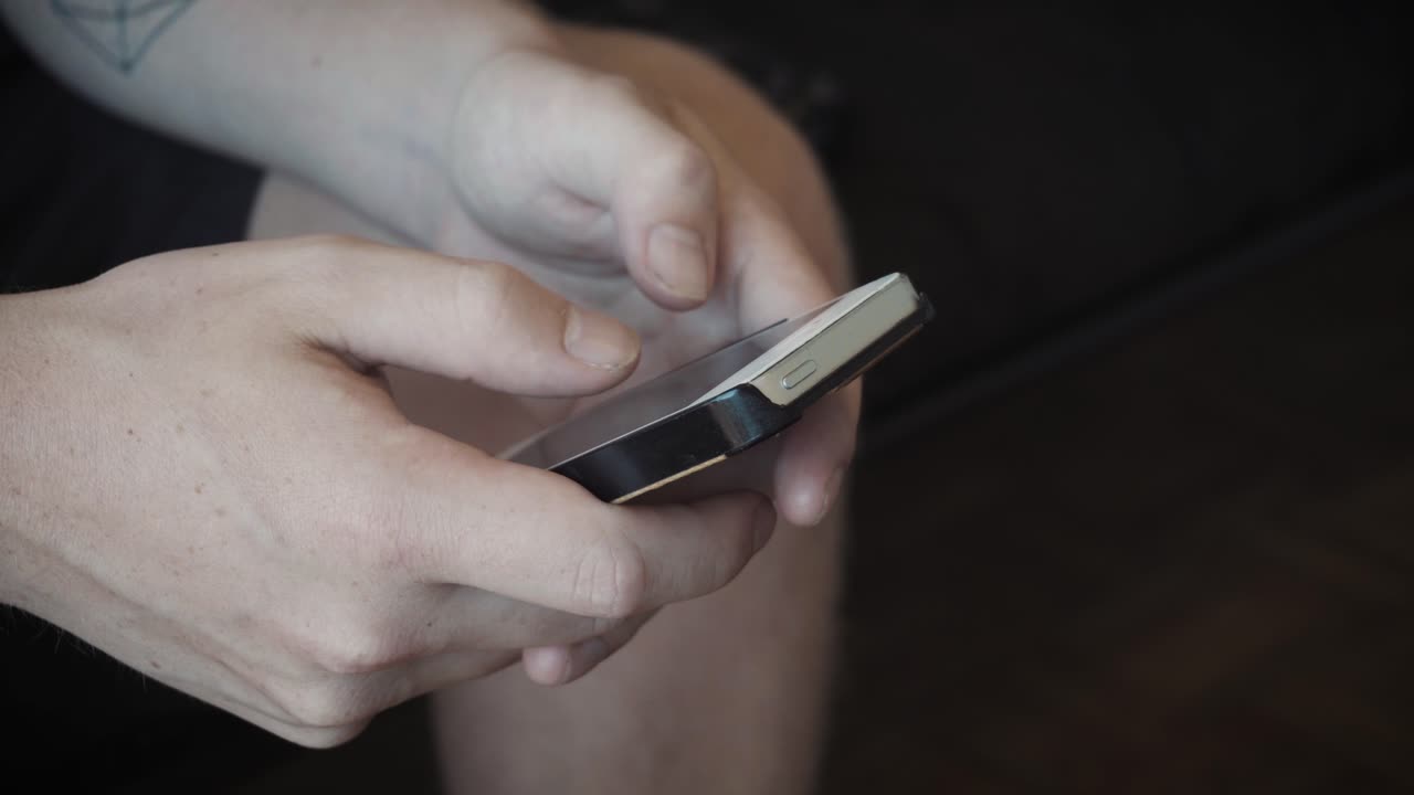 Static shot of a man texting and navigating a smart phone.
