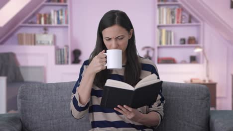 verwirrtes indisches mädchen liest ein buch und trinkt kaffee