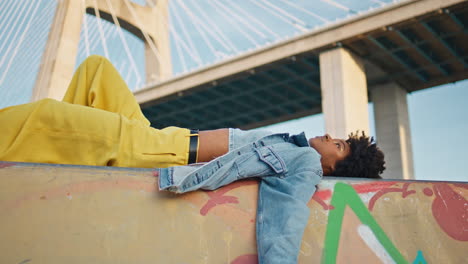 black haired girl lying city street in front bridge close up. woman posing town