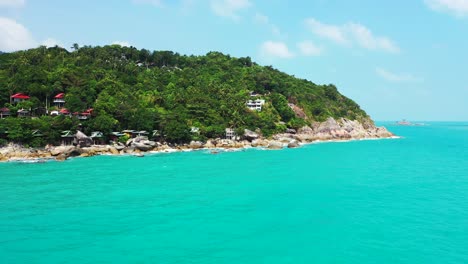 round island in the turquoise calm waters with colorful bungalows between palms