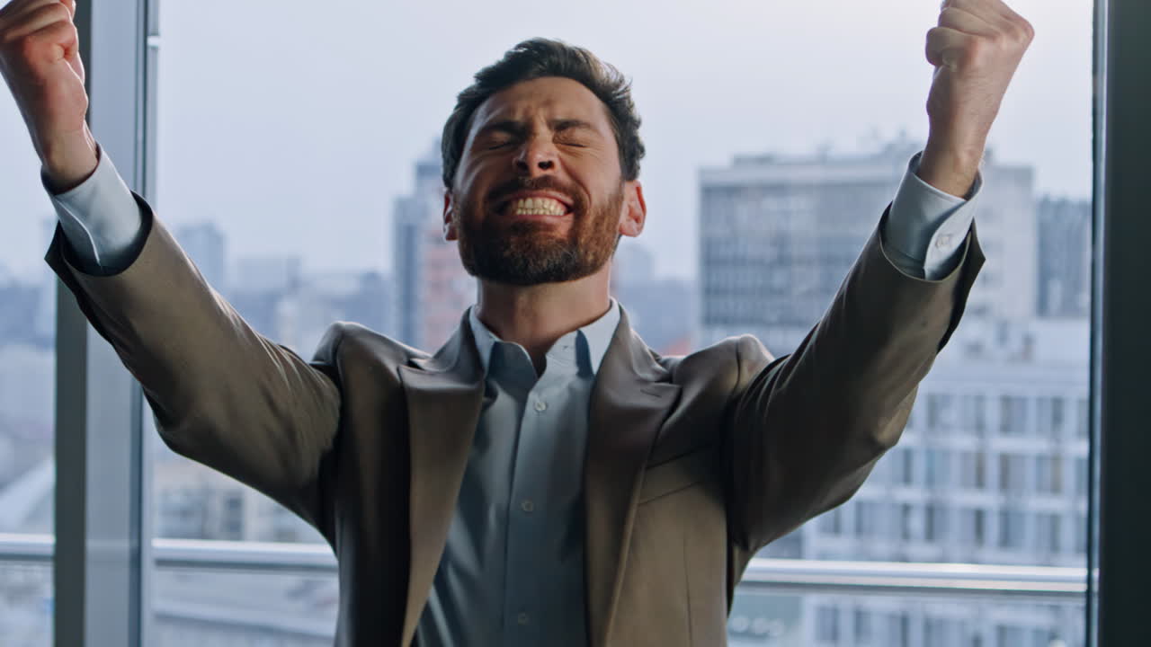 Excited winner rejoicing business success at huge windows office portrait