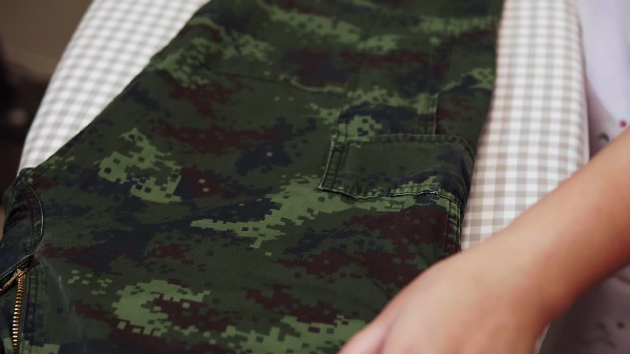 슬로우 모션 장면으로 집에 있는 스트림 다리미로 옷을 다림질하는 여성의 근접 촬영