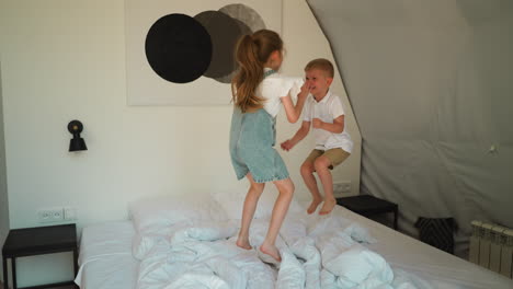 children jump on soft bed at glamping. active little boy and girl play having fun in eco hotel bedroom. naughty kids in luxury camping cabin