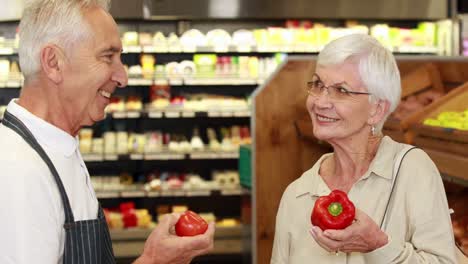 senior customer and worker discussing vegetables in grocery store