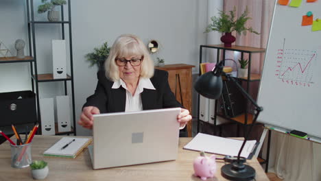 happy elderly business woman dancing victory dance celebrating weekend holiday success win in office