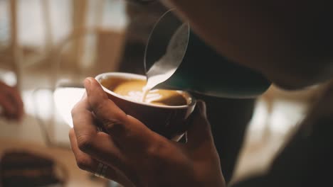 barista pouring milk into a cappuccino.