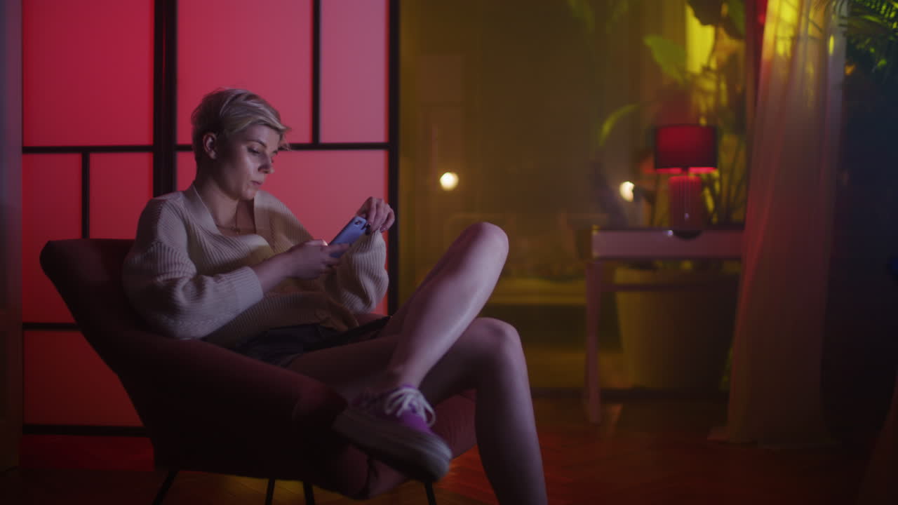 Donna che usa il telefono in un soggiorno colorato di notte