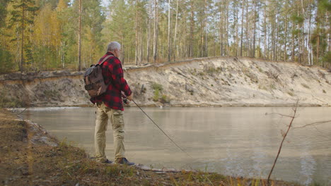 Pesca-Con-Caña-En-Agua-Dulce-Del-Río-En-Otoño-El-Pescador-Está-Usando-Caña-Y-Parado-En-La-Orilla-Carrete-Giratorio