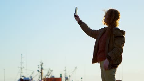 woman taking selfie with mobile phone at dock 4k