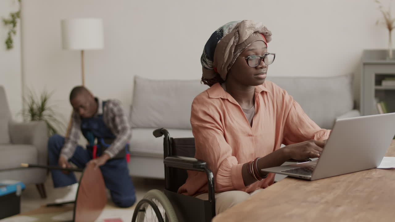 Handicapped Woman Working on Laptop while Carpenter Assembling Table