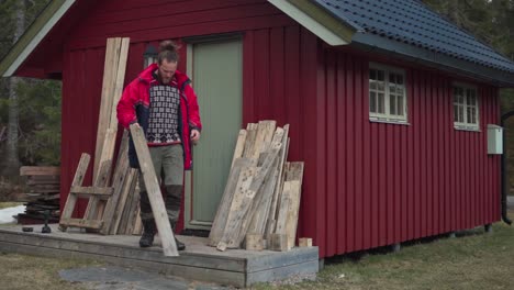 caucasian guy with wooden planks near rural cottage