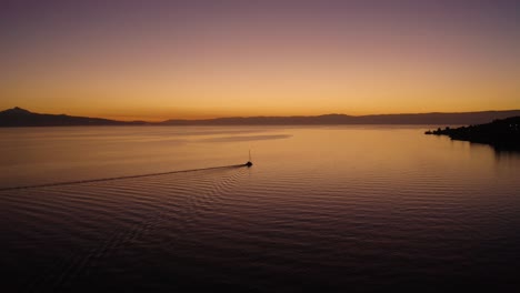 orbiting sailboat on lake léman with beautiful sunset colors in front of cully, lavaux - switzerland, the alps in the background