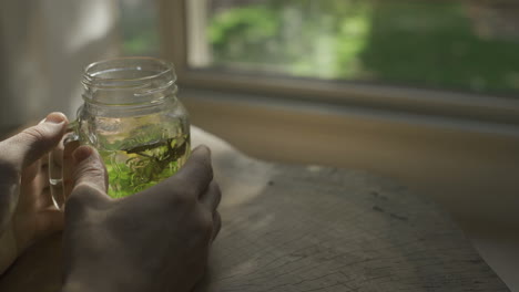 setting down a glass with herbal tea on wooden table