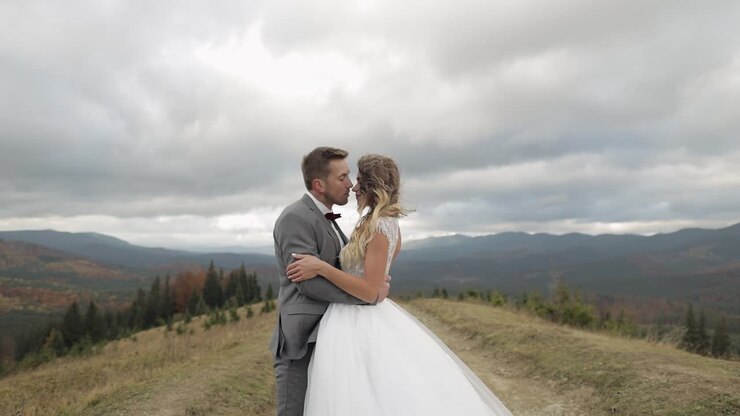 Lovely young newlyweds bride groom walking on mountain slope, making a kiss, wedding couple family