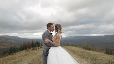 lovely young newlyweds bride groom walking on mountain slope, making a kiss, wedding couple family