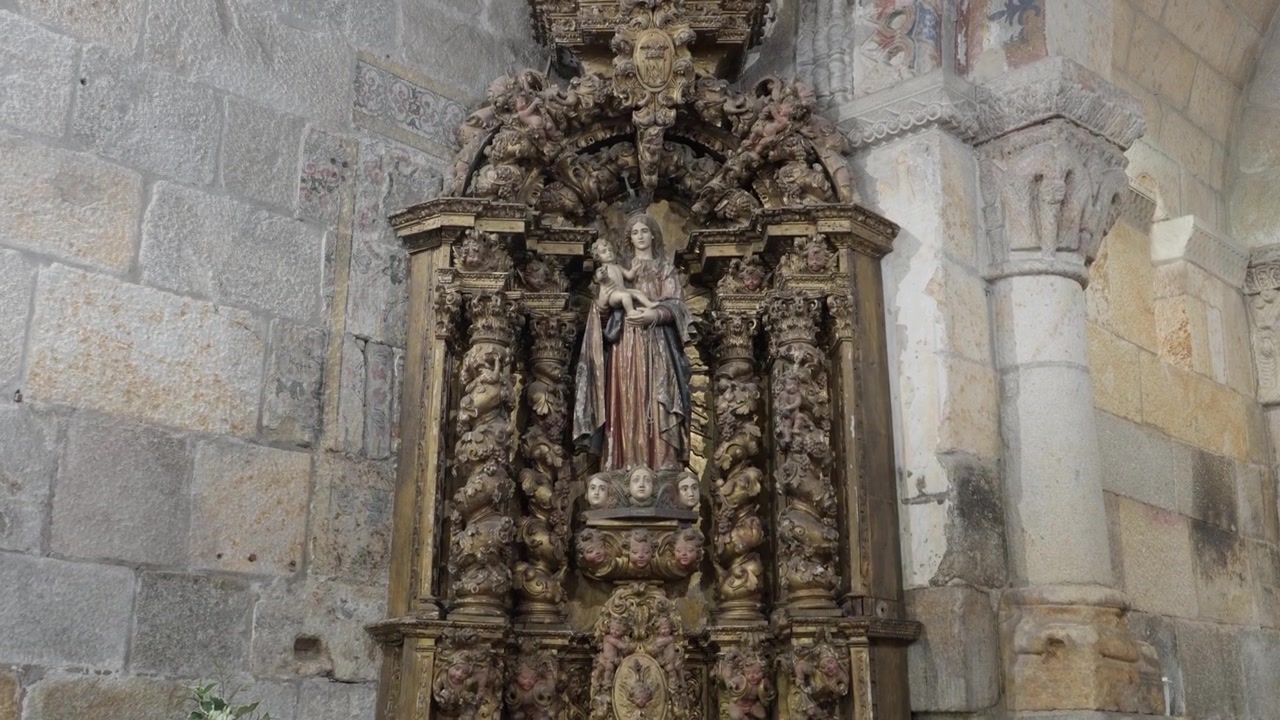 Pala d'altare barocca in legno dorato che sorregge una statua della Vergine con Bambino su una parete di chiesa in granito