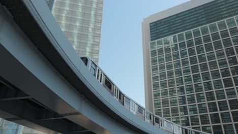 looking up wide angle of the tokyo monorail yurikamome passing by on a sunny day with skyscrapers in the background