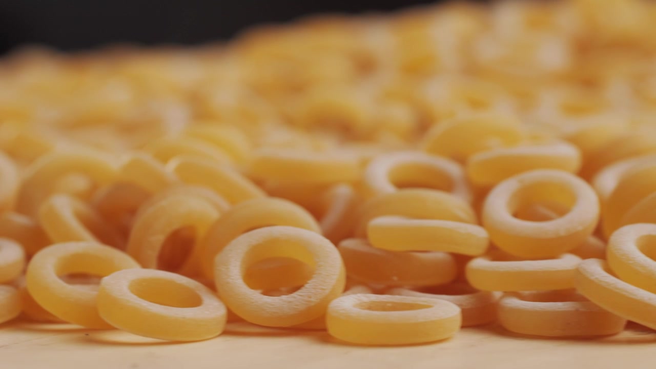 Pasta integrale biologica, maccheroni di semola di grano duro, penne rigate crude in una ciotola di legno. Filmato 4k di alta qualità