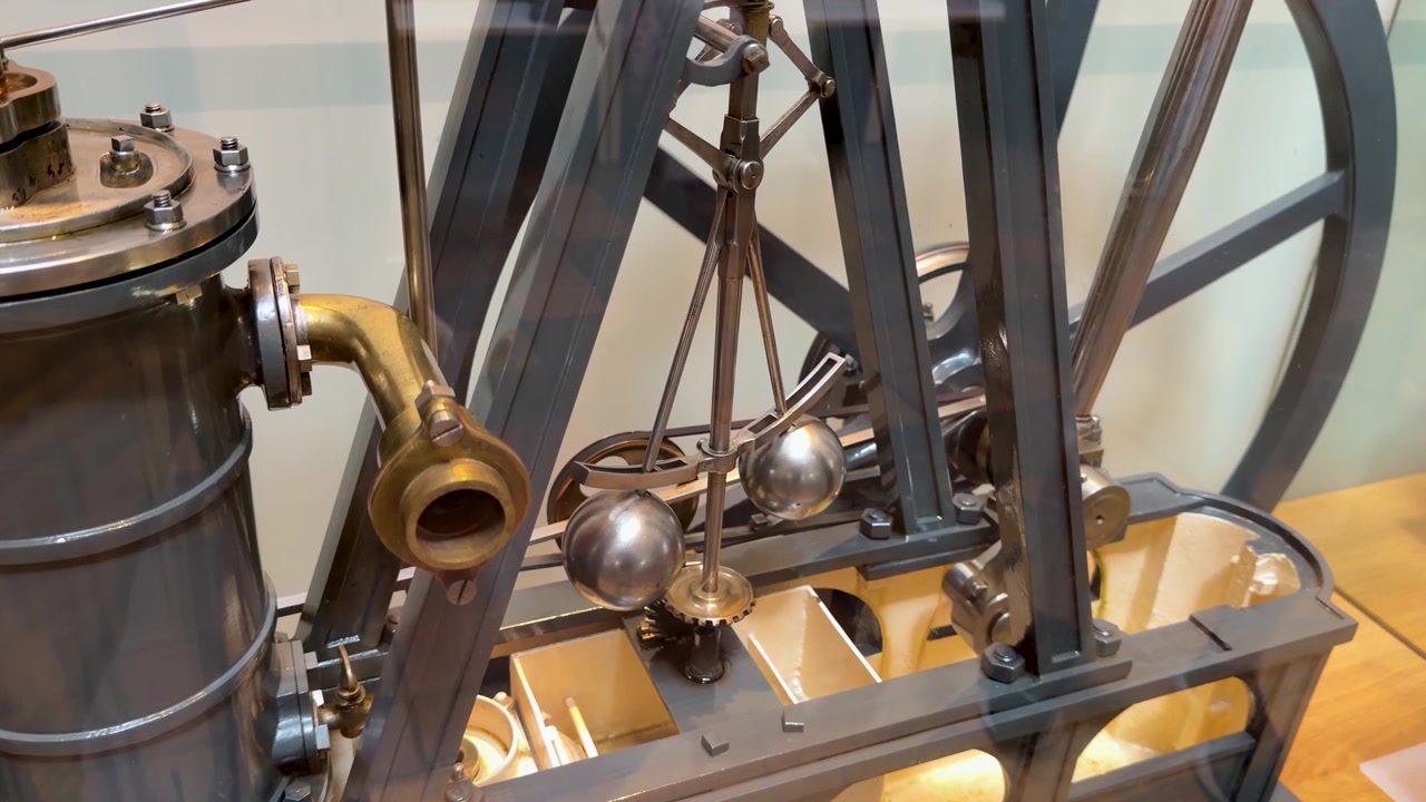 Detailní záběr zblízka zachycuje mechanický pohyb modelu historického parního stroje.