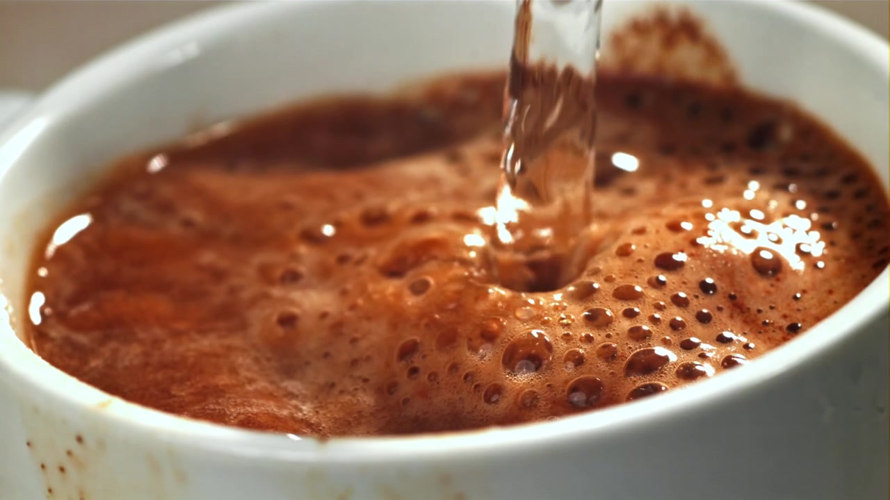 Primo piano di acqua calda versata in una miscela per bevanda marrone