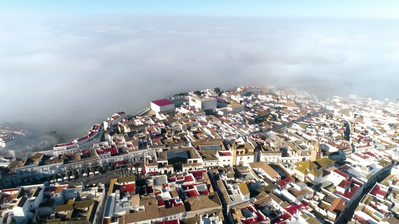 스페인의 구시가지 메디나 시도니아(medina sidonia) 너머로 느린 공중 돌리가 가끔 붉은 지붕이 있는 흰색 건물과 배경에 있는 구름이 있는 전체 구시가의 전망을 감상할 수 있습니다.