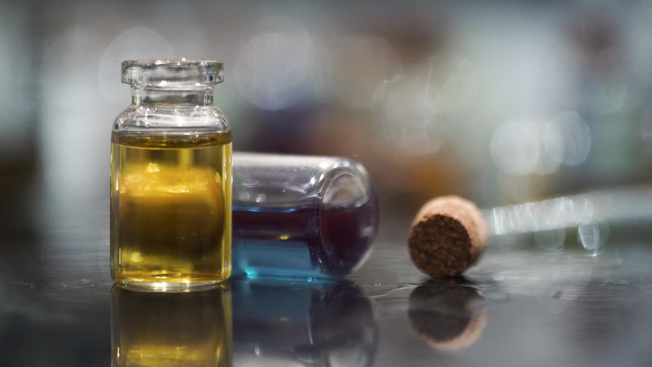 Small two glass bottles yellow blue liquid macro close up no action