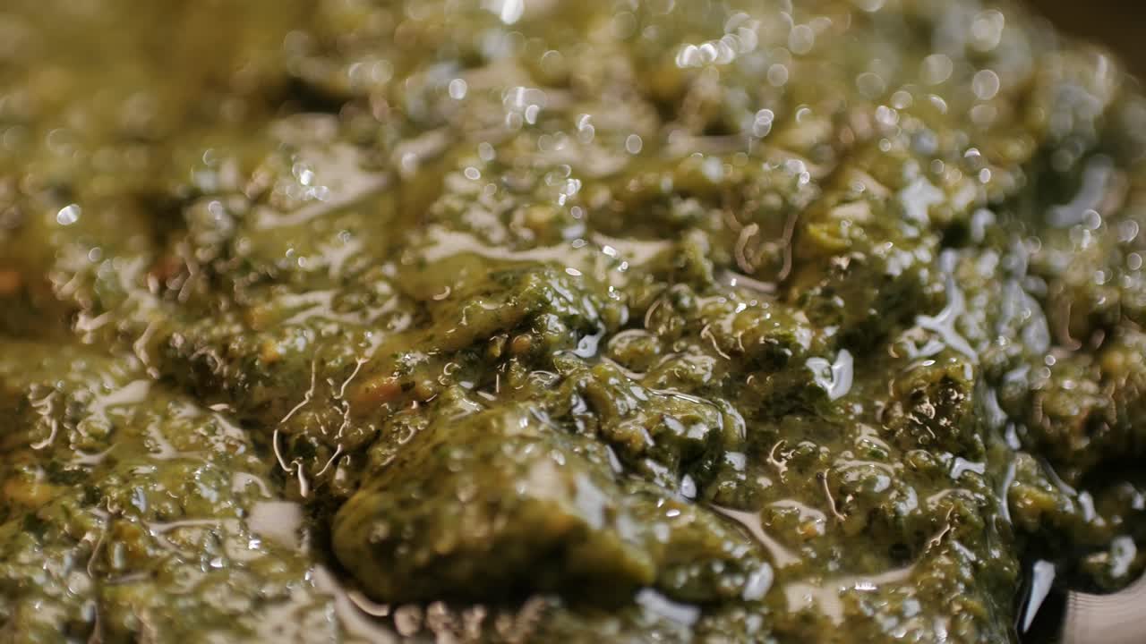 Cooking green pesto sauce close-up. Italian Pesto is a sauce that traditionally consists of crushed garlic, European pine nuts, coarse salt, basil leaves, and hard cheese such as Parmigiano-Reggiano, Parmesan or Pecorino Sardo all blended with olive oil. High quality 4k footage