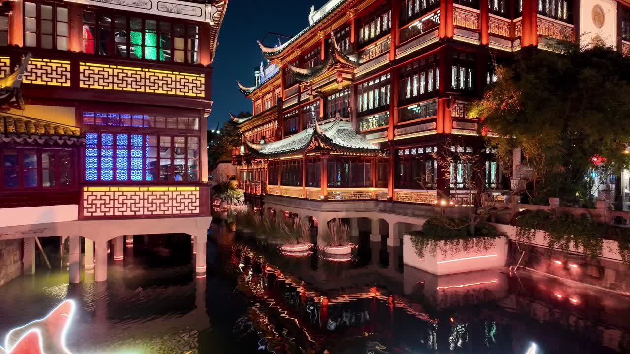 Traditional buildings in Yuyuan Shanghai glow with lights at night along the canal