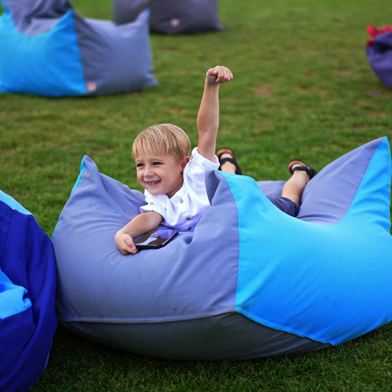 Cute cheerfull kid outdoor playing with phone. Little happy child having fun with smartphone