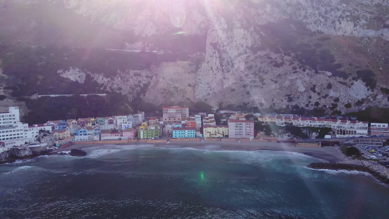 태양 플레어가 보이는 해변가에 화려한 건물이 있는 카탈루냐 만에서 부서지는 파도의 공중 전망