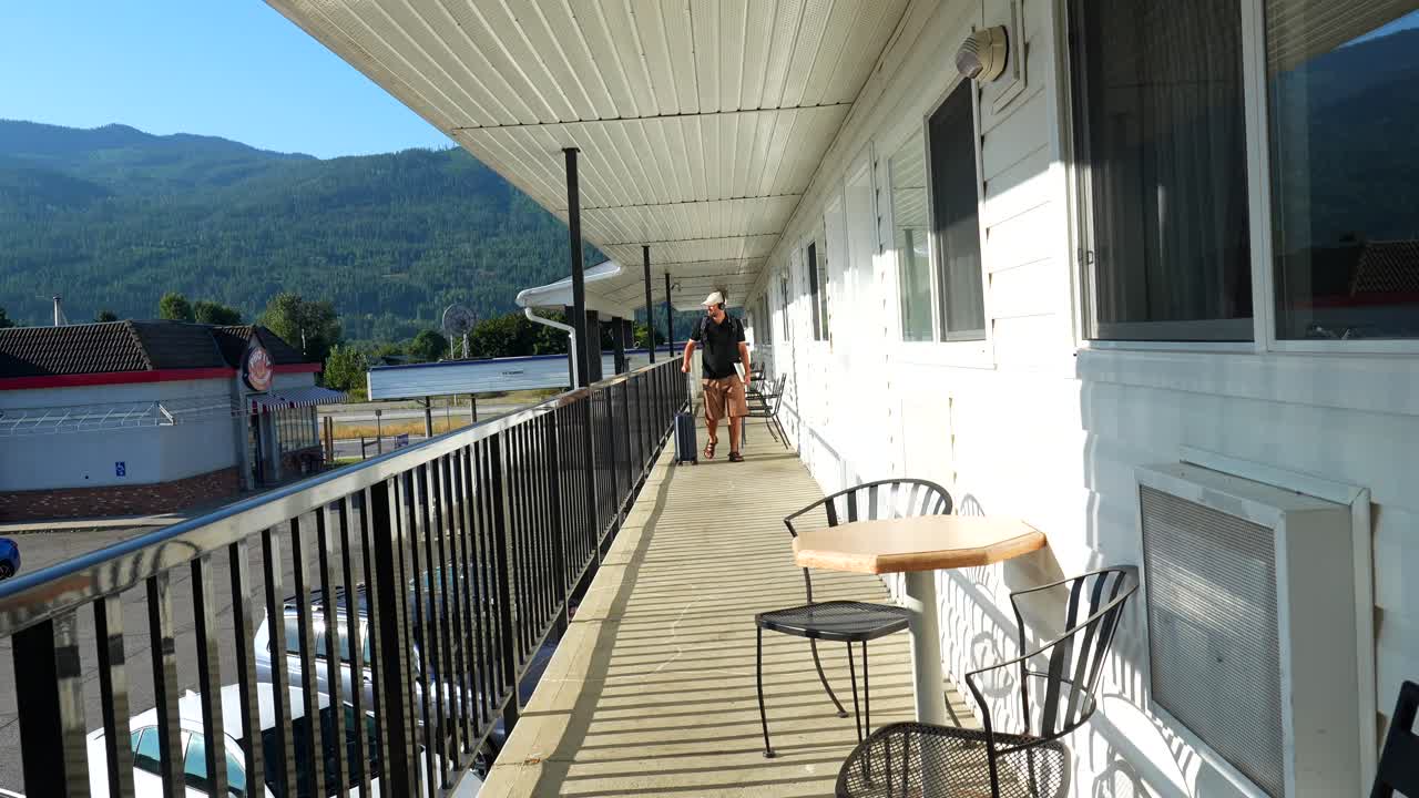 Uomo con bagagli sul balcone di un motel