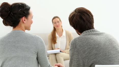 therapist smiling at reconciled couple holding hands