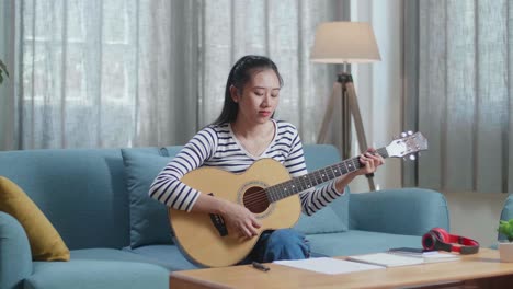 woman playing acoustic guitar at home