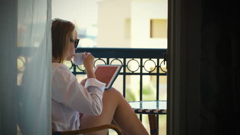 young woman with touchpad on hotel balcony