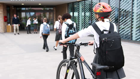 group of high school students wearing uniform arriving at school walking or riding bikes