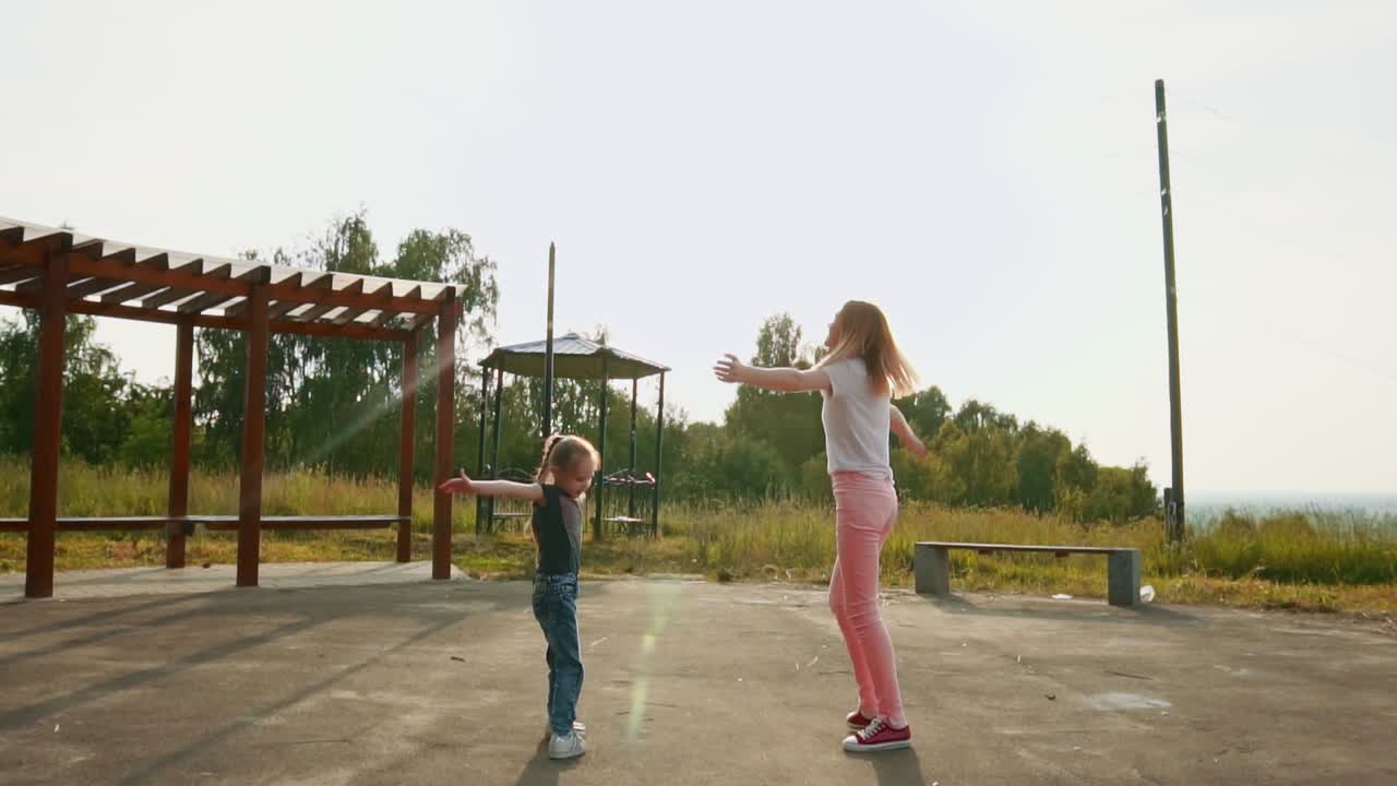 Mom and daughter whirl, dance in the sun. Summer sun and cheerful mood. Smiles and joy. 4K