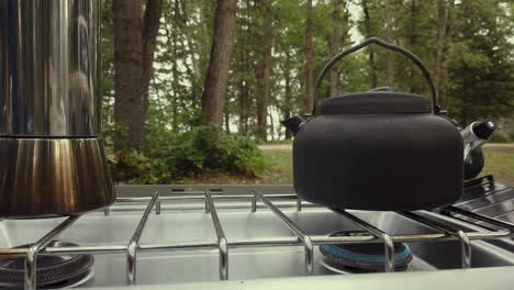 camping kettle with steam on a stove with low fire outdoor