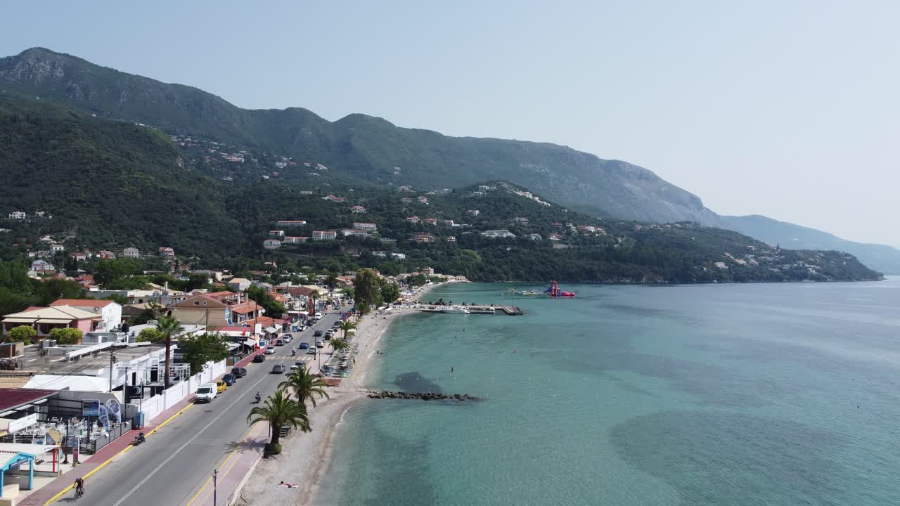 Dolly in low altitude flight over Ipsos Beach in Corfu, Greece, showing clear, transparent blue waters